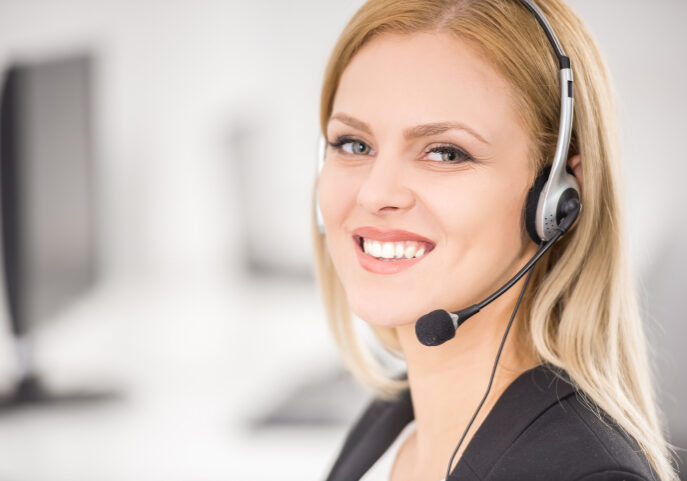 Attractive young woman in suit sitting at call center office and working.